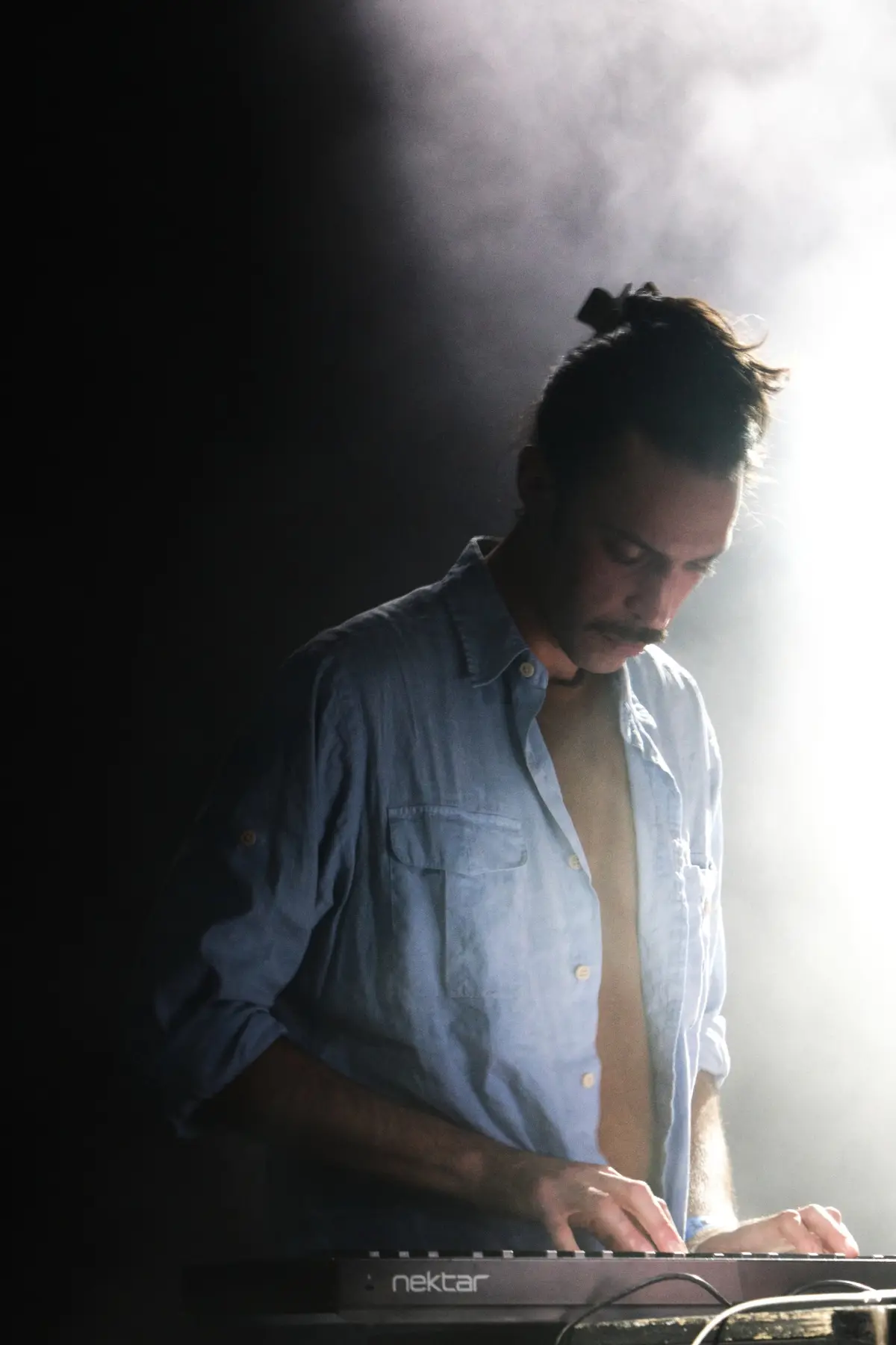 Ruben playing keys on stage, backlit through haze