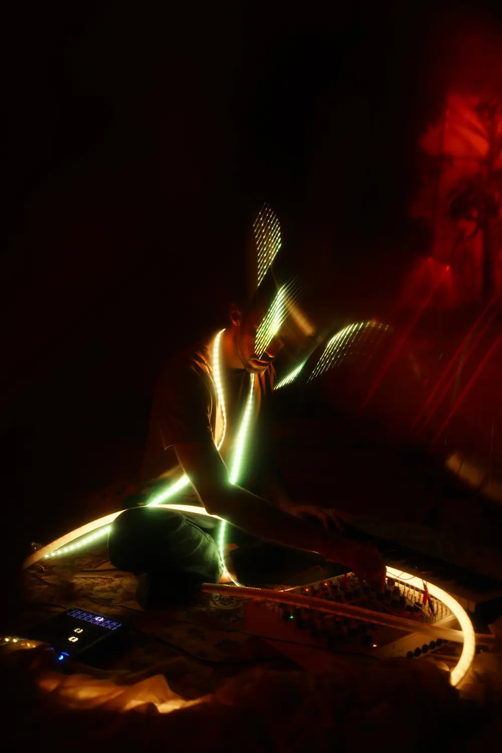 Ruben seated among synthesizers, wrapped in glowing light strips